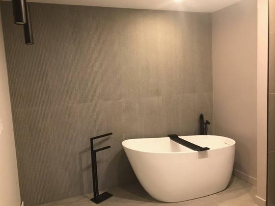Bain autoportant devant un mur de céramique grand format
