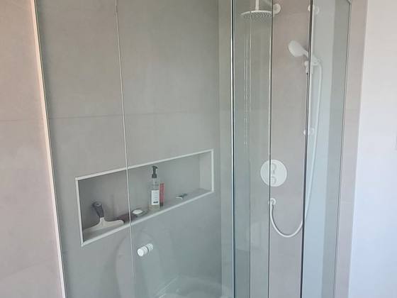Douche d'angle vitrée dans une petite salle de bain